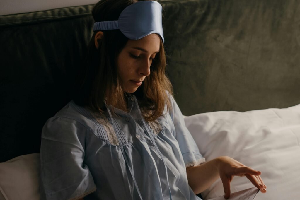 A woman in pajamas and sleep mask relaxing in bed, creating a cozy atmosphere.